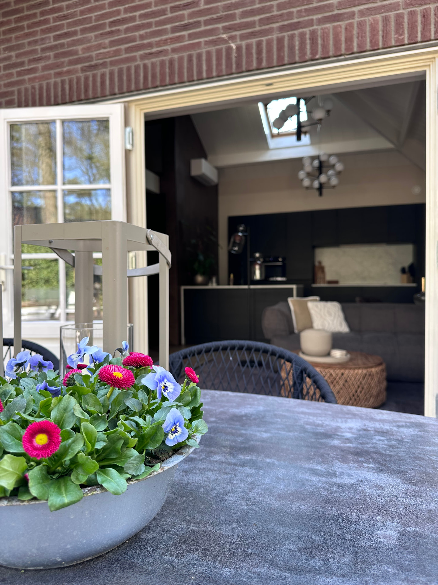 Terras met bloemen en doorkijk naar de woonkeuken van de suite