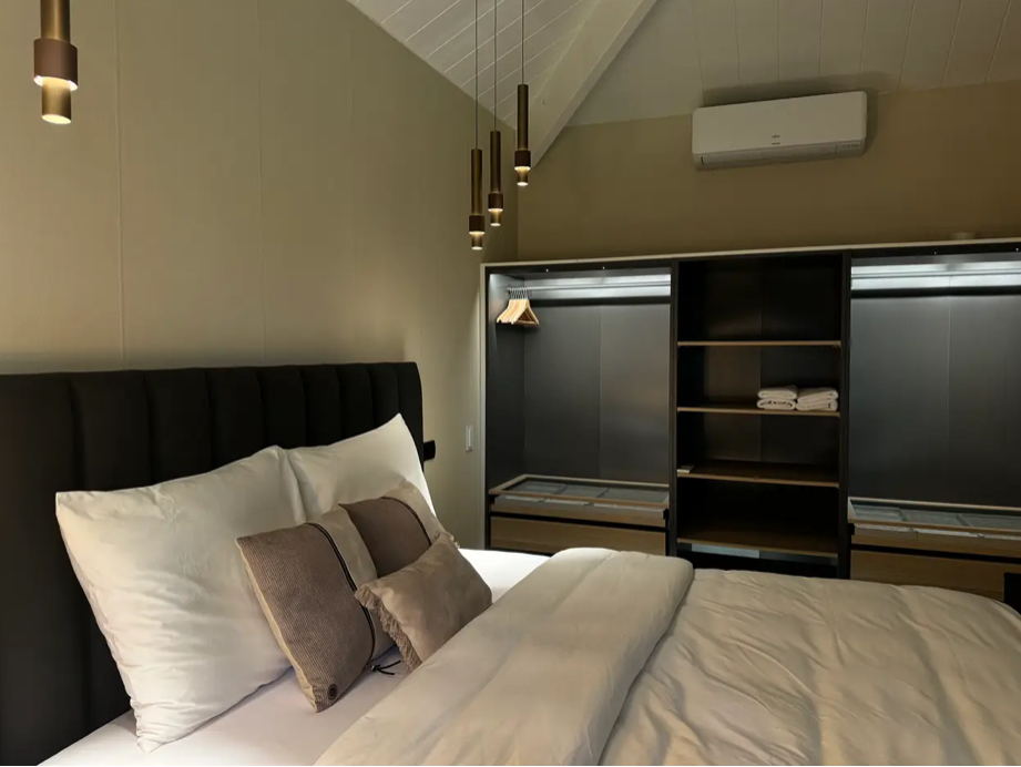 Slaapkamer met opgemaakt bed en verlichte kastwand